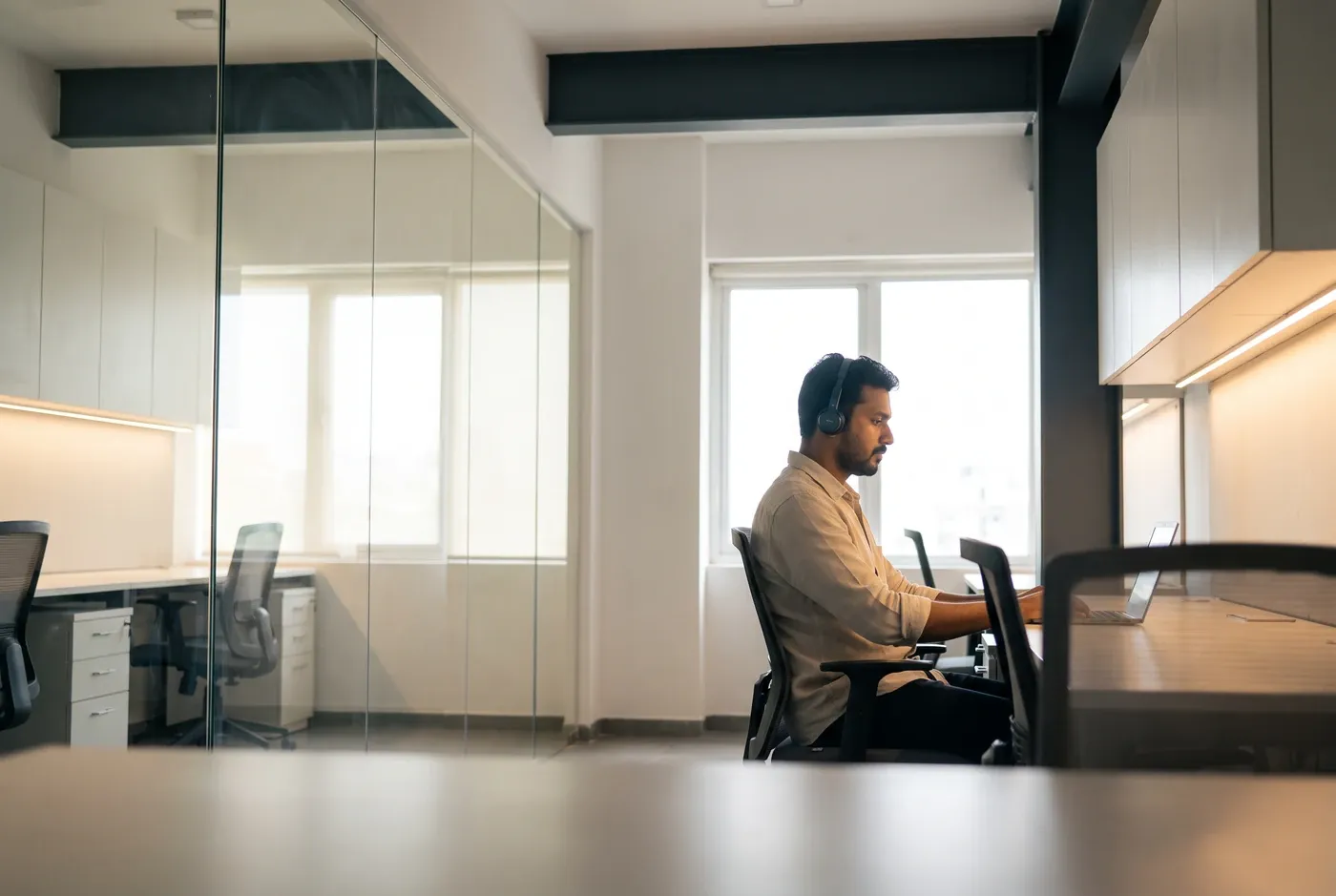 A person seated alone in a dim room, seen in profile